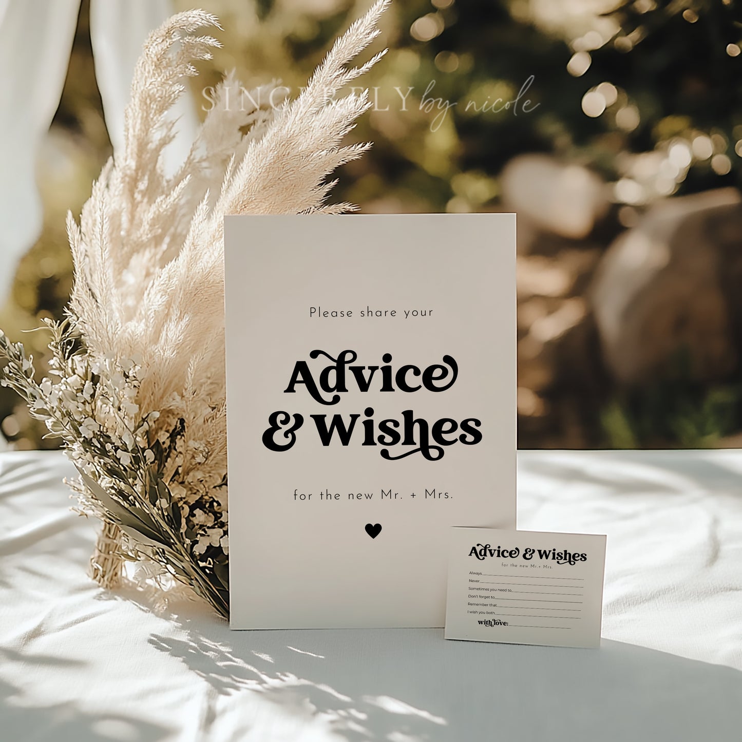 Elegant wedding advice and wishes sign with bold typography, displayed among neutral-toned florals and pampas grass. A matching advice card accompanies the sign, set on a softly lit reception table. A stylish touch for gathering heartfelt messages from guests.